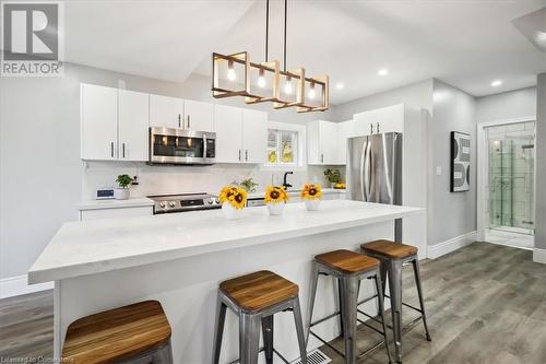 Kitchen featuring hardwood / wood-style flooring, a kitchen bar, white cabinetry, and appliances with stainless steel finishes - 59 Stanley Street, Brantford, ON - Indoor Photo Showing Kitchen With Stainless Steel Kitchen With Upgraded Kitchen