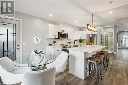 Kitchen featuring stainless steel appliances, dark wood-type flooring, a center island, white cabinets, and hanging light fixtures - 59 Stanley Street, Brantford, ON - Indoor