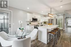 Kitchen featuring stainless steel appliances, dark wood-type flooring, a center island, white cabinets, and hanging light fixtures - 