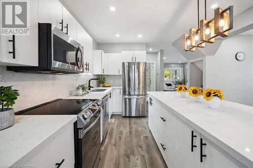 Kitchen with white cabinetry, stainless steel appliances, light hardwood / wood-style floors, and decorative light fixtures - 59 Stanley Street, Brantford, ON - Indoor Photo Showing Kitchen With Stainless Steel Kitchen With Upgraded Kitchen