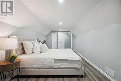 Bedroom with dark wood-type flooring and lofted ceiling - 