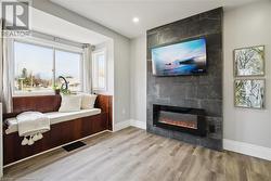 Sitting room with a tiled fireplace and light hardwood / wood-style floors - 