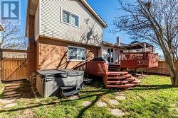 Back of property featuring a hot tub, a lawn, and a wooden deck - 