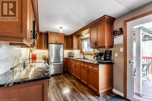 Kitchen with new stone counters, decorative backsplash, sink, and new flooring, appliances with stainless steel finishes - 56 Imperial Road N, Guelph, ON - Indoor Photo Showing Kitchen