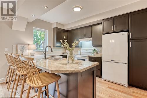 Kitchen with decorative backsplash, sink, light stone countertops, light wood-type flooring, and white appliances - 262 Homewood Avenue, Hamilton, ON - Indoor Photo Showing Kitchen