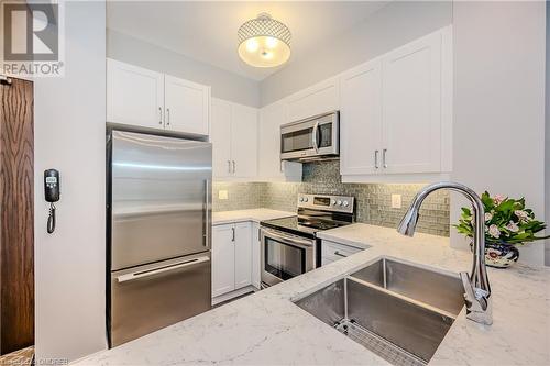 Kitchen featuring white cabinetry, sink, backsplash, and appliances with stainless steel finishes - 2511 Lakeshore Road W Unit# 108, Oakville, ON - Indoor Photo Showing Kitchen With Double Sink With Upgraded Kitchen