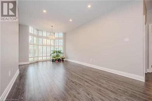 Unfurnished room featuring an inviting chandelier and dark hardwood / wood-style floors - 2511 Lakeshore Road W Unit# 108, Oakville, ON - Indoor