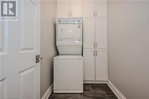 Laundry room featuring cabinets and stacked washer and dryer - 2511 Lakeshore Road W Unit# 108, Oakville, ON - Indoor Photo Showing Laundry Room