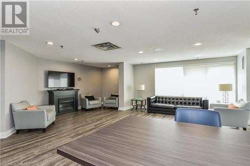 Living room featuring a fireplace, a textured ceiling, and hardwood / wood-style floors - 2511 Lakeshore Road W Unit# 108, Oakville, ON - Indoor With Fireplace