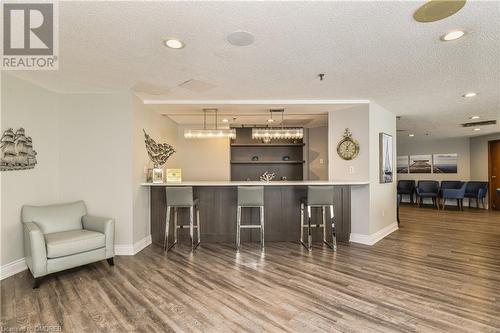 Bar featuring dark wood-type flooring, a textured ceiling, and pendant lighting - 2511 Lakeshore Road W Unit# 108, Oakville, ON - Indoor