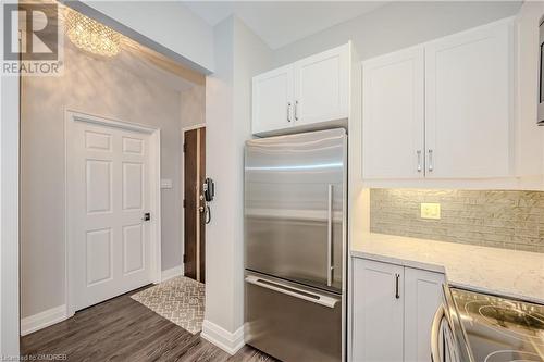 Kitchen with stainless steel appliances, dark hardwood / wood-style flooring, light stone countertops, decorative backsplash, and white cabinets - 2511 Lakeshore Road W Unit# 108, Oakville, ON - Indoor