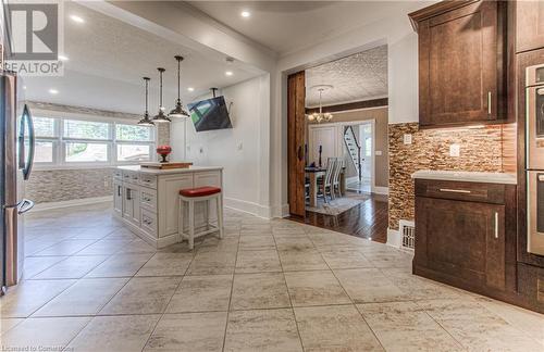 Kitchen featuring white cabinetry, ornamental molding, a kitchen breakfast bar, a textured ceiling, and stainless steel fridge - 52 Adam Street, Cambridge, ON - Indoor Photo Showing Kitchen