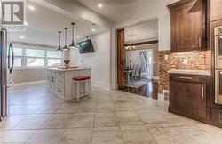 Kitchen featuring white cabinetry, ornamental molding, a kitchen breakfast bar, a textured ceiling, and stainless steel fridge - 