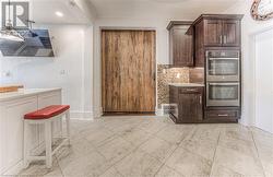 Kitchen with ornamental molding, dark brown cabinetry, tasteful backsplash, and double oven - 