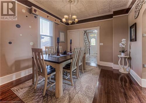 Dining area featuring dark wood-type flooring, a wealth of natural light, an inviting chandelier, and crown molding - 52 Adam Street, Cambridge, ON - Indoor Photo Showing Dining Room