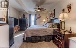 Bedroom featuring beamed ceiling, ceiling fan, and light colored carpet - 