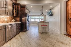 Kitchen featuring tasteful backsplash, appliances with stainless steel finishes, dark brown cabinets, and a breakfast bar - 