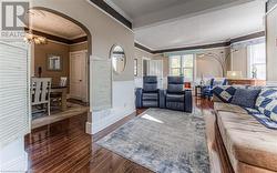 Living room with dark hardwood / wood-style flooring, a notable chandelier, and ornamental molding - 