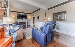 Living room featuring dark wood-type flooring and ornamental molding - 