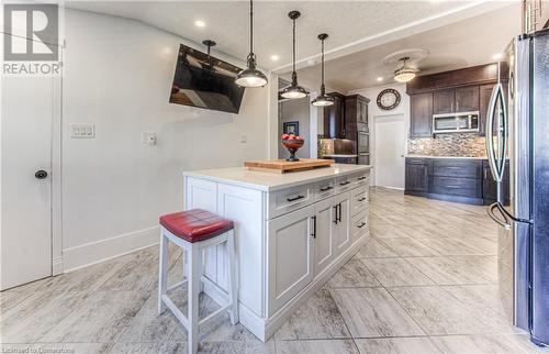 Kitchen with stainless steel appliances, a center island, white cabinets, dark brown cabinetry, and backsplash - 52 Adam Street, Cambridge, ON - Indoor Photo Showing Kitchen