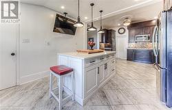 Kitchen with stainless steel appliances, a center island, white cabinets, dark brown cabinetry, and backsplash - 