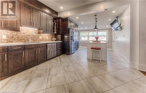 Kitchen with stainless steel appliances, sink, tasteful backsplash, dark brown cabinets, and decorative light fixtures - 52 Adam Street, Cambridge, ON - Indoor