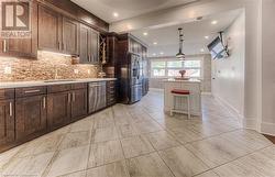 Kitchen with stainless steel appliances, sink, tasteful backsplash, dark brown cabinets, and decorative light fixtures - 