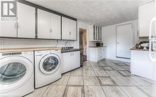 Laundry area with light tile patterned floors, cabinets, sink, and washing machine and clothes dryer - 52 Adam Street, Cambridge, ON - Indoor Photo Showing Laundry Room