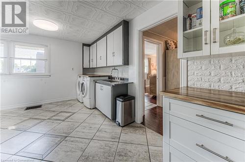 Laundry room featuring cabinets, separate washer and dryer, sink, and light tile patterned flooring - 52 Adam Street, Cambridge, ON - Indoor Photo Showing Other Room