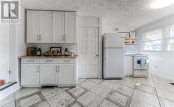 Kitchen with butcher block counters, white cabinetry, electric stove, white refrigerator, and decorative backsplash - 