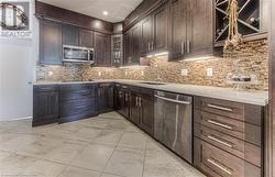 Kitchen with stainless steel appliances, dark brown cabinets, sink, and backsplash - 