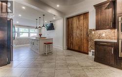 Kitchen featuring stainless steel appliances, crown molding, a textured ceiling, a kitchen bar, and hanging light fixtures - 