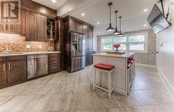 Kitchen featuring stainless steel appliances, sink, a kitchen breakfast bar, a kitchen island, and pendant lighting - 