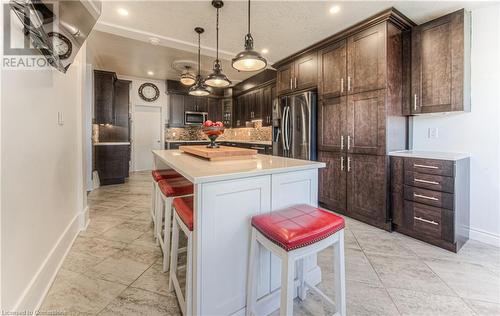 Kitchen featuring dark brown cabinetry, appliances with stainless steel finishes, a kitchen breakfast bar, a textured ceiling, and a center island - 52 Adam Street, Cambridge, ON - Indoor Photo Showing Kitchen