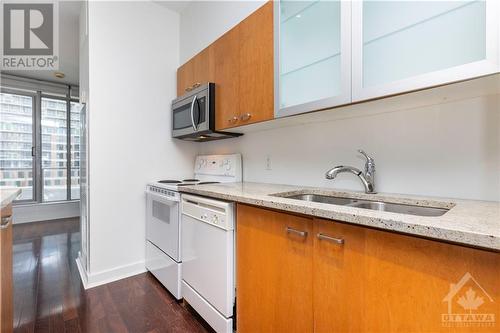 In the heart of Ottawa, this stylish condo features a flexible kitchen island, hardwood floors, and sweeping views from the private patio. - 383 Cumberland Street Unit#710, Ottawa, ON - Indoor Photo Showing Kitchen With Double Sink