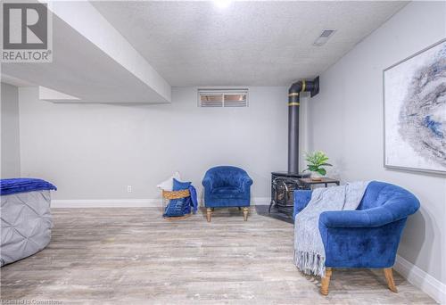 Sitting room featuring light wood-type flooring, a wood stove, and a textured ceiling - 83 Bridlewreath Street, Kitchener, ON - Indoor