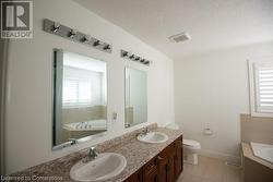 Bathroom featuring toilet, tile patterned floors, a tub, a textured ceiling, and vanity - 