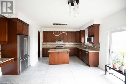 Kitchen featuring appliances with stainless steel finishes, decorative backsplash, sink, an inviting chandelier, and a center island - 839 Autumn Willow Drive, Waterloo, ON - Indoor Photo Showing Kitchen