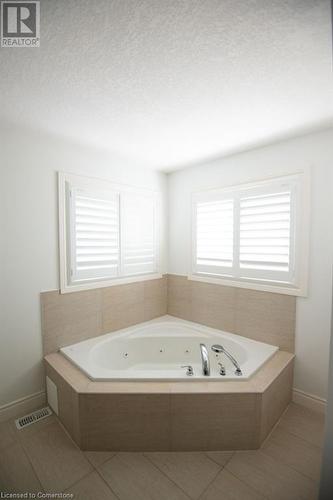 Bathroom with a relaxing tiled tub, a textured ceiling, and tile patterned floors - 839 Autumn Willow Drive, Waterloo, ON - Indoor Photo Showing Bathroom