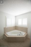 Bathroom with a relaxing tiled tub, a textured ceiling, and tile patterned floors - 