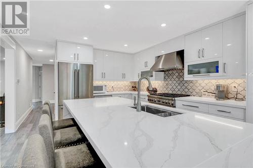 Kitchen with high end refrigerator, white cabinetry, a breakfast bar area, wall chimney exhaust hood, and light wood-type flooring - 139 Shady Pine Circle, Brampton, ON - Indoor Photo Showing Kitchen With Upgraded Kitchen