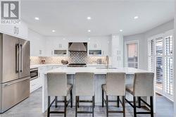 Kitchen featuring white cabinets, stainless steel appliances, wall chimney exhaust hood, and sink - 