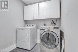 Clothes washing area with light wood-type flooring, cabinets, and separate washer and dryer - 