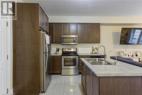 Kitchen featuring appliances with stainless steel finishes, a textured ceiling, sink, an island with sink, and light tile patterned flooring - 135 Samuel Drive, Arthur, ON 