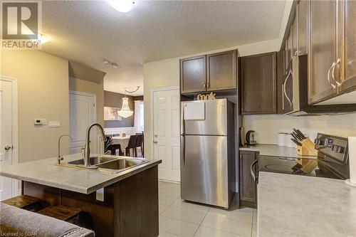 Kitchen featuring a kitchen breakfast bar, a textured ceiling, stainless steel appliances, sink, and decorative light fixtures - 135 Samuel Drive, Arthur, ON 