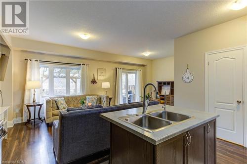 Kitchen featuring sink, dark hardwood / wood-style floors, a textured ceiling, dark brown cabinets, and a center island with sink - 135 Samuel Drive, Arthur, ON 