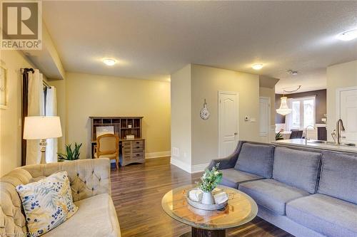 Living room with a textured ceiling, dark wood-type flooring, and sink - 135 Samuel Drive, Arthur, ON 