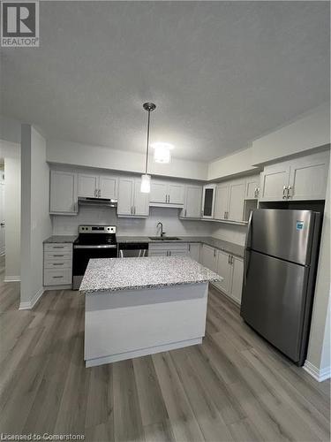 Kitchen featuring stainless steel appliances, pendant lighting, light stone counters, and light hardwood / wood-style flooring - 25 Isherwood Avenue Unit# 42, Cambridge, ON 