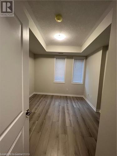 Unfurnished room featuring wood-type flooring, a textured ceiling, and a raised ceiling - 25 Isherwood Avenue Unit# 42, Cambridge, ON 