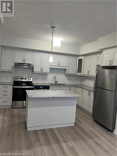 Kitchen featuring stainless steel appliances, decorative backsplash, sink, pendant lighting, and light wood-type flooring - 25 Isherwood Avenue Unit# 42, Cambridge, ON 